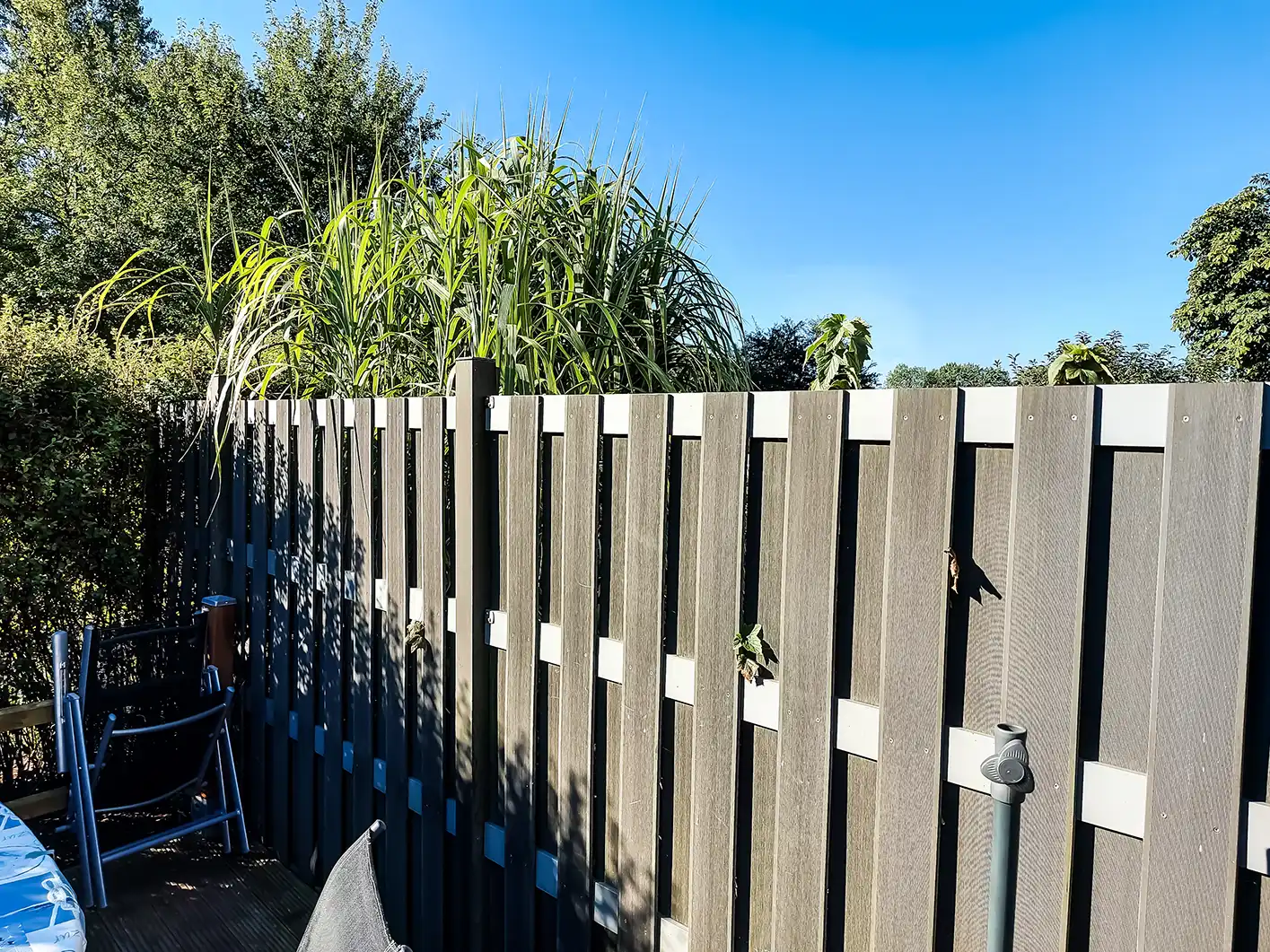 Moderner Lamellenzaun als Wind- und Sichtschutz entlang einer Terrasse